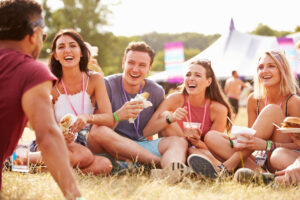 featured image showing friends sitting on the grass and eating food at a festival