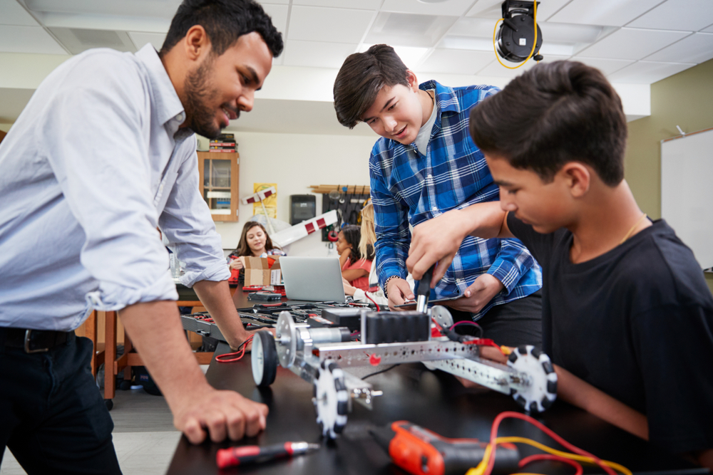 Featured image showing a teach with two male students building a robot in the classroom