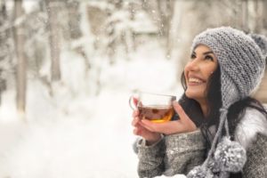 Featured image showing a woman standing in the snow holding a cup of apple cider