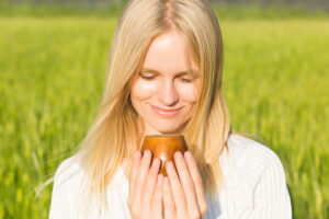 Featured image showing a young woman in a green field holding a cup of tea.