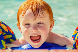 Featured image showing a 2 year old boy with red hair swimming in a pool with floaties in Reno, Nevada