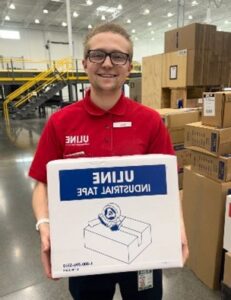 Featured image showing Issac, an intern at Uline holding a shipping box in the Uline warehouse.