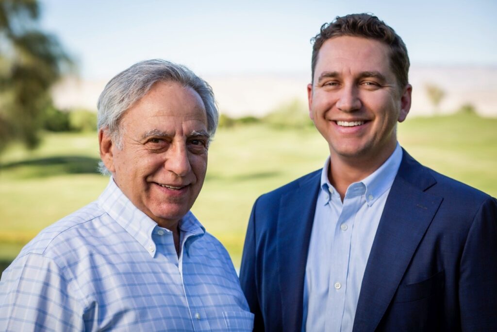 Featured image showing Alan and Alex Altman, a father and son duo, owners of Protoqual, dressed in business casual standing together on a golf course smiling.
